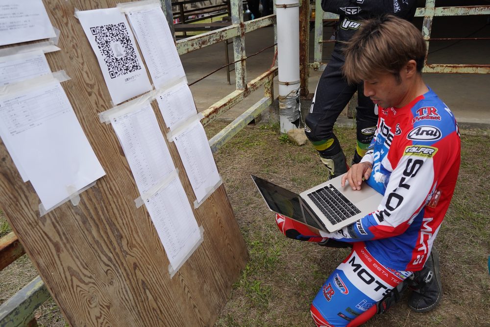 速報と本部発表の結果を見比べている小川毅士。ライダーのかっこうをしているけどアプリ制作者としてのお仕事。結果には、わずかなちがいがあった。スマホの入力まちがいかパンチのうちまちがいか、その両方か、もはやわからない。もちろんルール上、正式結果が正しい。